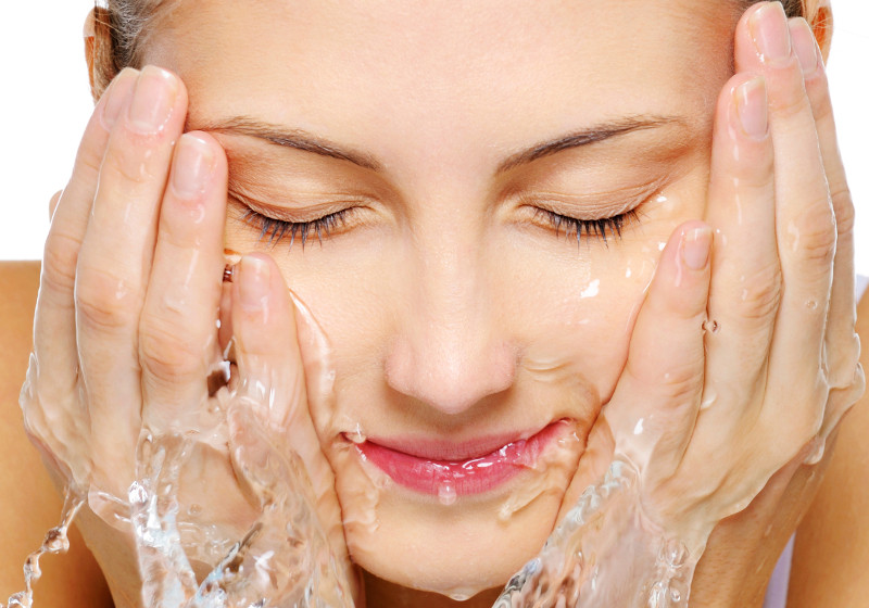 Close-up portrait of a cute young woman wash her  face with water