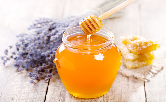 jar of honey with honeycomb and lavander flowers